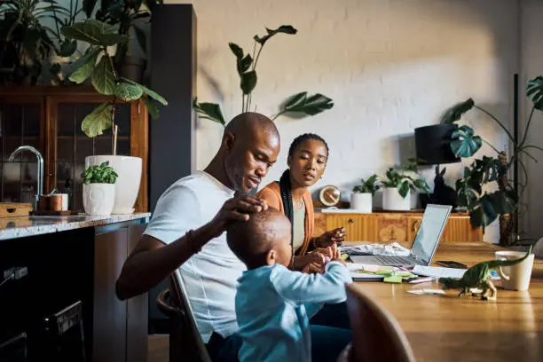 Photo of Family, children and budget with a couple using a laptop to invest or manage savings in the dining room of their home together. Kids, insurance and finance with a black man and woman managing wealth