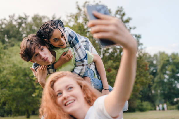 Best friends taking selfie having fun together outdoor, enjoying carefree lifestyle. Multiethnic friendship. Modern technology. stock photo