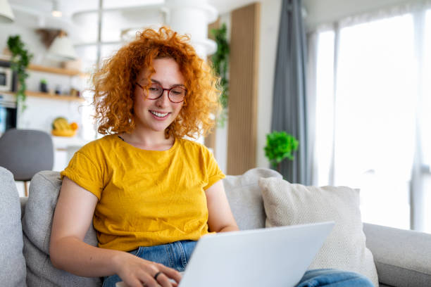 istock Woman sitting with computer on sofa, studying at home, e-learning and remote freelance job concept 1438562026