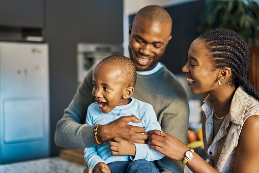 Black family, father and mother hug child, happy together at home, spending quality time and bonding. Black woman, man and kid, fun and love, playful and childhood, parents and son laughing.