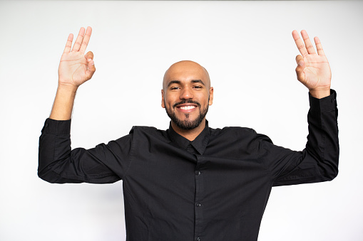 Portrait of happy young businessman showing ok gesture against white background. Young bearded man wearing black shirt looking at camera and smiling. Success and approval concept