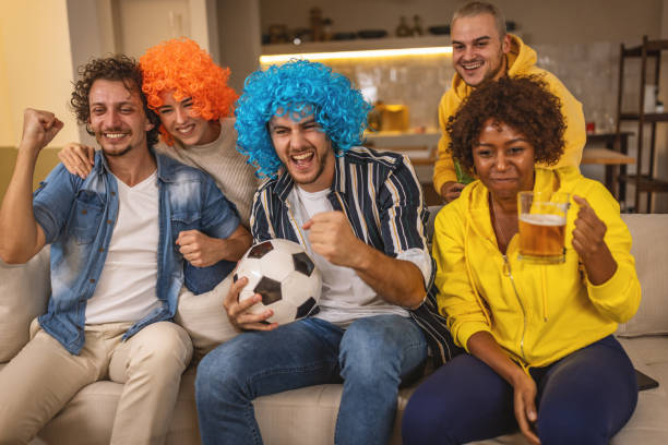 istock Soccer fans emotionally watching game at home. 1438565408