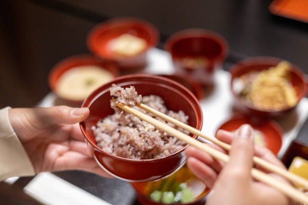 Female tourist eating 'sekihan' red bean rice using chopsticks stock photo