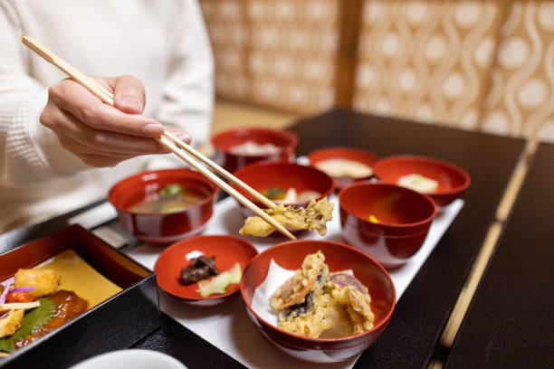 Female tourist picking up tempura using chopsticks