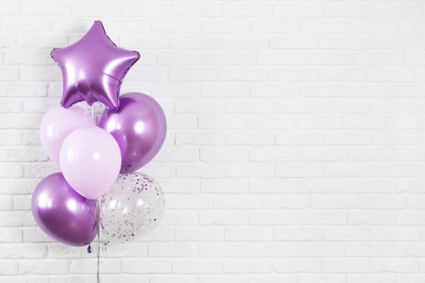 Bunch of purple balloons on white brick wall texture background stock photo