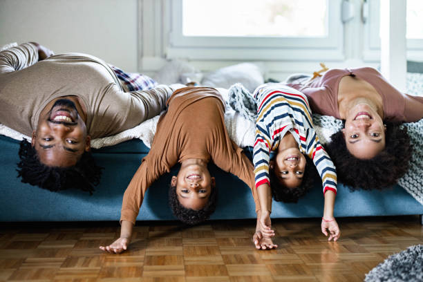 glückliche afroamerikanische familie liegt kopfüber auf einem bett. - women group of people lying down mother stock-fotos und bilder