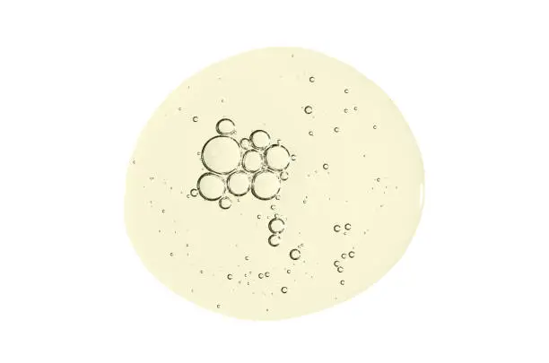 Photo of A drop of body serum or cosmetic oil with bubbles. Liquid skin care product. Isolated on a white background.