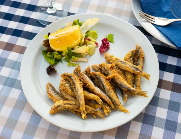 Photo of Fried in batter anchovies with fresh vegetables and lemon