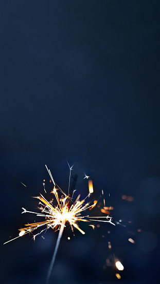 yellow sparkle with sparks on dark blue background, copy space, vertical, 16:9
