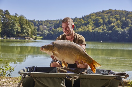 A male demonstrating the giant fish caught in the Smartinsko lake, municipality Celje, Savinjska region, Slovenia
