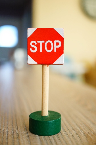 A small red stop sign on a wooden table under the lights with a blurry background