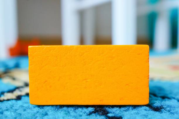 оранжевая прямоугольная игрушка для детей, нанесенная на разноцветную поверхность - babelsberg стоковые фото и изображения