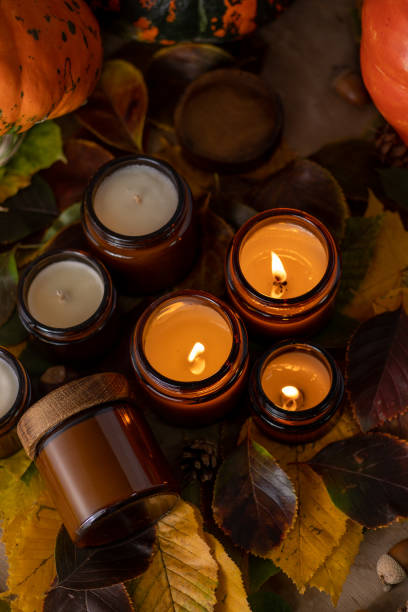 Soy candles burn in glass jars. Tree leaves. Comfort at home. Candle in a brown jar. Scent and light. Scented handmade candle. Aroma therapy. Autumn mood. Cozy home decor in fall. Festive decoration. las velas de soja arden en frascos de vidrio. hojas de árbol. comodidad en casa. vela en un frasco marrón. aroma y luz. vela perfumada hecha a mano. aromaterapia. estado de ánimo otoñal. acogedora decoración del hogar en otoño. decoración festiva