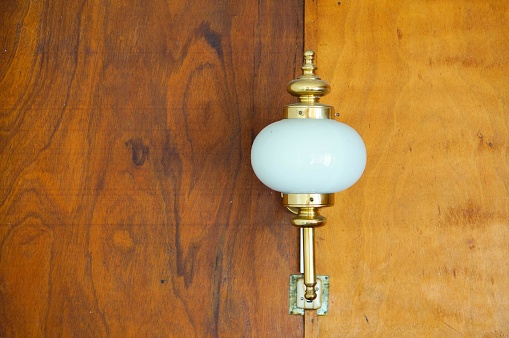 An old lamp on a wooden wall under the lights in a house