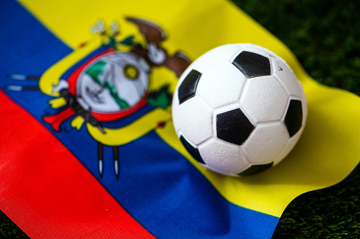 Ecuador national football team. National Flag on green grass and soccer ball. Football wallpaper for Championship and Tournament in 2022. World international match.