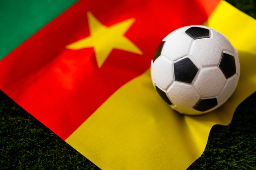 Cameroon national football team. National Flag on green grass and soccer ball. Football wallpaper for Championship and Tournament in 2022. World international match.