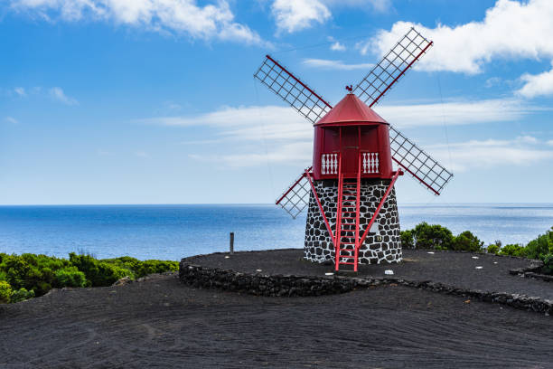 moulin à vent rouge sur la côte de pico avec un ciel bleu clair aux açores - red mill photos et images de collection