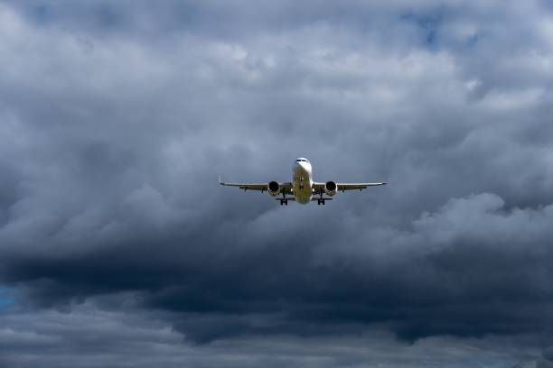 istock Low angle of a white passenger airplane in mid-air with cloudy background during daytime 1438576690