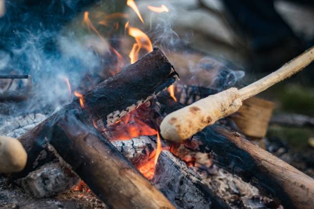 istock Bread dough on a wooden stick being cooked in a bonfire 1438578316