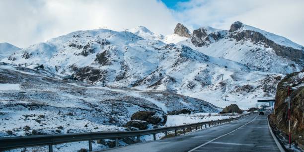 istock Narrow road surrounded by high rocky mountains covered with snow under a cloudy sky 1438578568