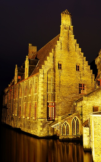A vertical shot of the medieval Hospital de San Juan in Bruges, Belgium at night