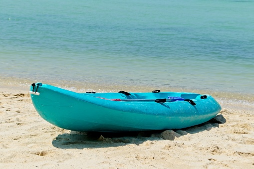 A blue row boat on the beach with the beautiful ocean in the background