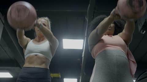 African woman doing exercises with a kettlebell in the gym with a personal trainer