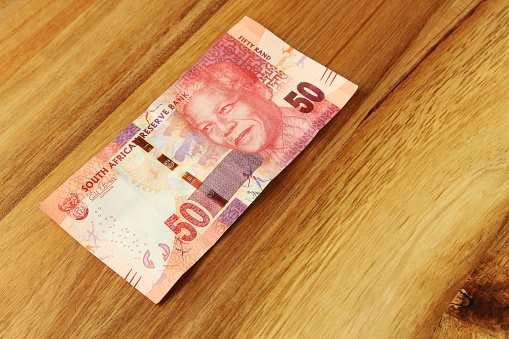 A high angle shot of a South African 50 rand bill on a wooden surface