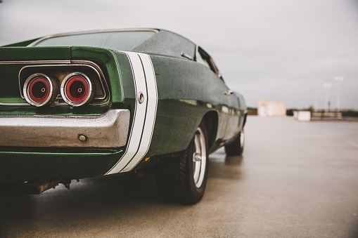 A closeup shot of a green muscle car on a blurred background
