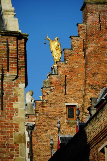 vista posteriore verticale della statua dorata di justitia in cima al vecchio tribunale di bruges, belgio - justice is blind foto e immagini stock