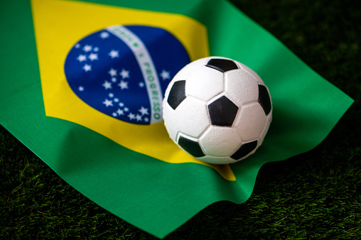 Brazil national football team. National Flag on green grass and soccer ball. Football wallpaper for Championship and Tournament in 2022. World international match.