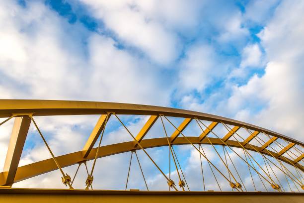 istock Low angle shot of a yellow cable-stayed bridge with a blue cloudy sky in the background 1438581796