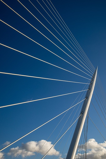 A vertical shot of a pole on a cable-stayed bridge with a blue sky in the background