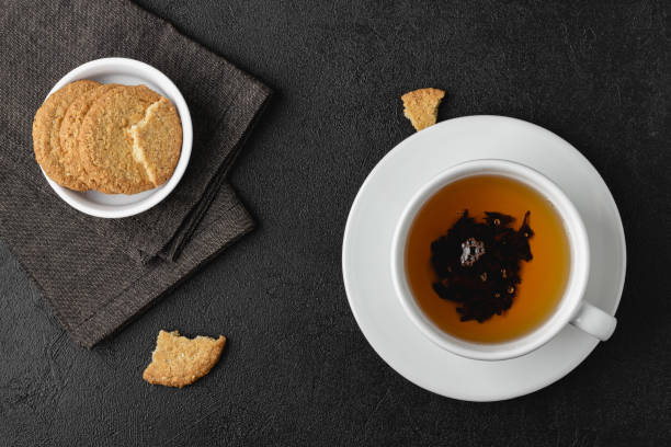 istock Cup of tea with cookies on black background. 1438583255