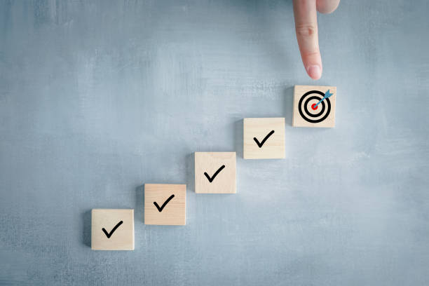 Checklist, Task list, Survey and assessment, Quality Control, Goals achievement and business success. To do list. Hand point to dartboard from top of step of complete with check mark on wooden block. lista de verificación, lista de tareas, encuesta y evaluación, control de calidad, logro de objetivos y éxito empresarial. lista de tareas pendientes. apunta a la diana desde la parte superior del escalón completo con marca de verificación en el bloqu