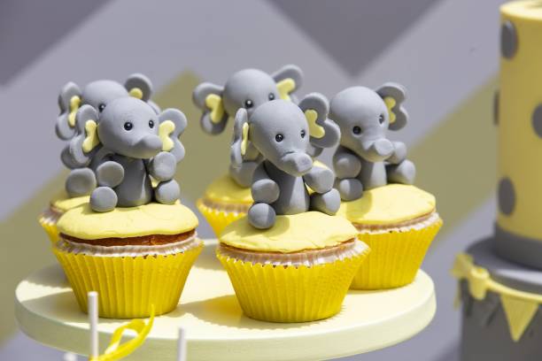 istock Closeup of cupcakes with small elephants on them under the lights with a blurred background 1438583702