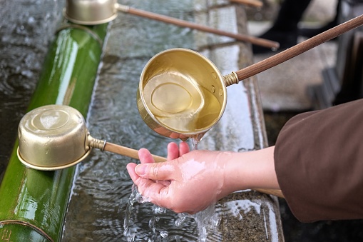 A person washing hands with saint water in a Japanese temple, Tokyo