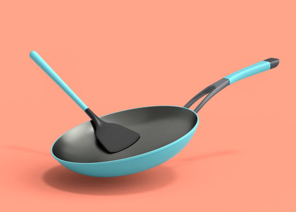 istock Frying pan with glass lid and silicon solid turner on coral background. 1438585245