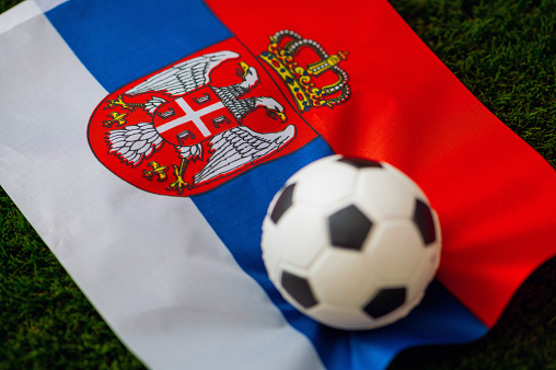 Serbia national football team. National Flag on green grass and soccer ball. Football wallpaper for Championship and Tournament in 2022. World international match.