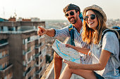 Happy tourists couple, friends sightseeing city with map together. Travel people concept.