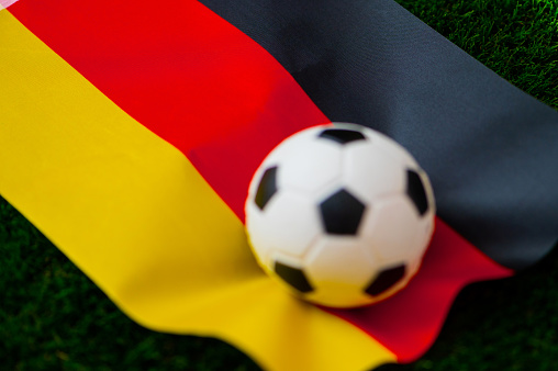 Germany national football team. National Flag on green grass and soccer ball. Football wallpaper for Championship and Tournament in 2022. World international match.
