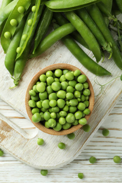 istock Bowl with pea seeds and fresh pea on wooden background 1438588446