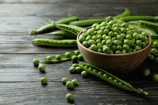 istock Bowl with fresh pea seeds on wooden background 1438588744