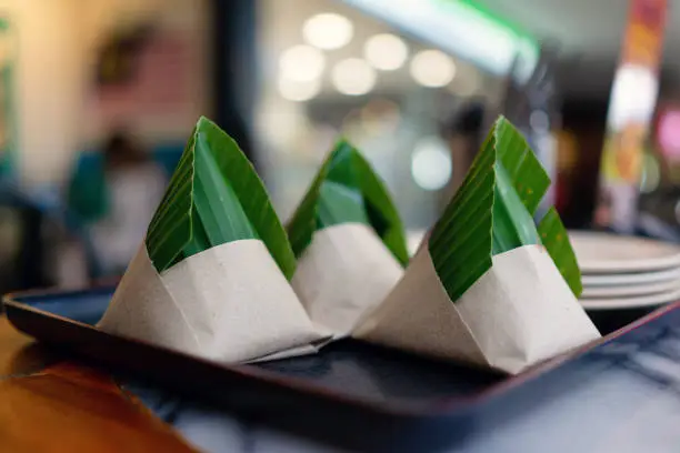 Photo of Nasi Lemak wrapped in paper and banana leaf, Malaysian popular food.