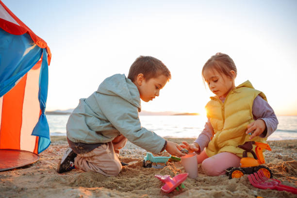 Little girl and boy playing with plastic toy set on the beach Happy little girl and boy building sandcastle on the beach sandcastle structure stock pictures, royalty-free photos & images