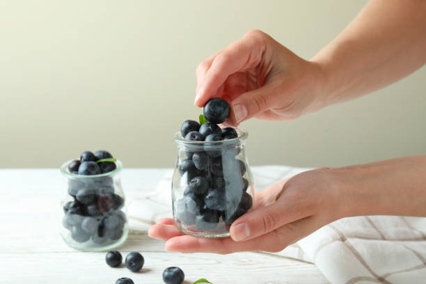 istock Female hands hold jar with blueberry, close up 1438591035