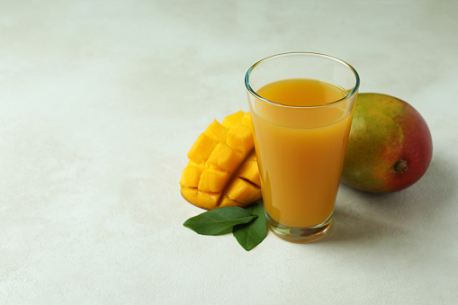 Ripe mango fruit and juice on white textured table