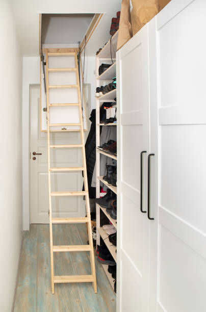 istock Wooden ceiling pull down attic folding stairs in small minimalist hallway corridor, space saving in home concept. 1438593747