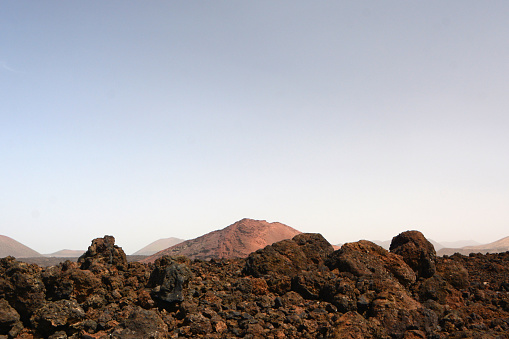 Volcanic landscape with in front a lava plain and single volcano and hill range