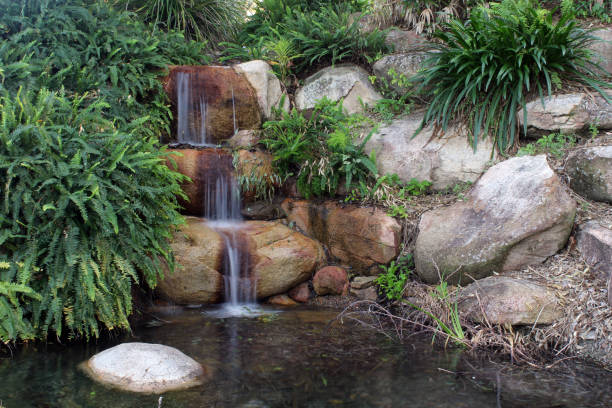 istock Small waterfall in a garden with rocks and plants 1438594785
